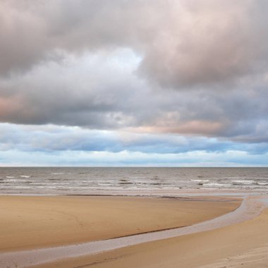Gün batımında Baltık kıyısı. Kumsal manzarası (kum tepeleri). Dramatik günbatımı gökyüzü, parlayan bulutlar. Idyllic manzara. Doğa, tatiller, eğlence. Çevre turizmi. Panoramik görünüm