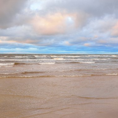 Gün batımında Baltık kıyısı. Kumsal manzarası (kum tepeleri). Dramatik günbatımı gökyüzü, parlayan bulutlar. Idyllic manzara. Doğa, tatiller, eğlence. Çevre turizmi. Panoramik görünüm