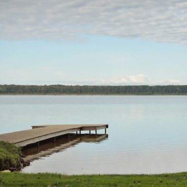 Orman nehri (göl) güneşli bir günde. Ahşap iskele. Clea gökyüzü, kristal berrak suda yansıyor. Idyllic manzara, kırsal manzara. Doğa, ekoloji, eko-turizm, yürüyüş, ekoloji beldesi, yerel turizm