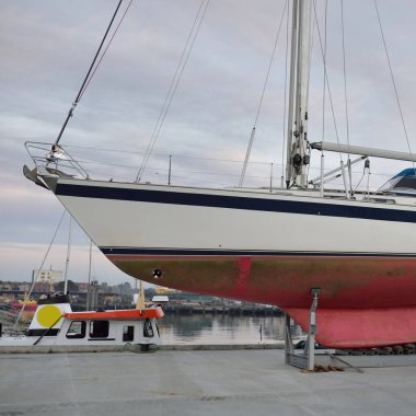 Bir yat limanında karada duran 20 metrelik bir yelkenli. Ulaşım, denizcilik, onarım ve hizmet, yelkencilik, spor, eğlence. Turizm, boş zaman aktivitesi kavramları