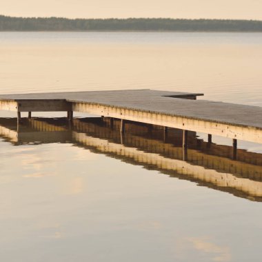 Orman Gölü (nehir) gün batımında. Ahşap iskele. Parlayan bulutlar, durgun ve berrak suda simetri yansımaları. Idyllic manzara. Doğa, ekoloji, ekolojik rezerv, eko-turizm, yürüyüş, tatiller