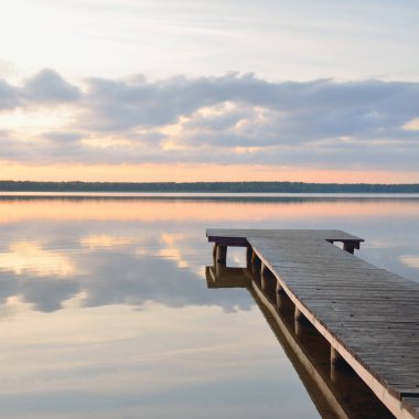 Orman Gölü (nehir) gün batımında. Ahşap iskele. Parlayan bulutlar, durgun ve berrak suda simetri yansımaları. Idyllic manzara. Doğa, ekoloji, ekolojik rezerv, eko-turizm, yürüyüş, tatiller
