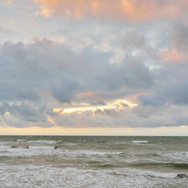Gün batımında Baltık kıyılarından panoramik manzara. Dramatik bulutlar, parlayan bulutlar, fırtınadan sonra altın güneş ışığı. Doğa, çevre, iklim değişikliği, kararsız hava