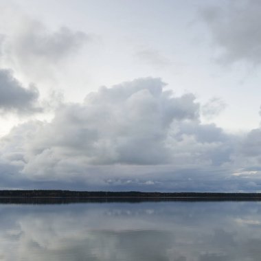 Forest river (lake) at sunset. Dramatic sky, dark glowing clouds. Symmetry reflections in a crystal clear water. Panoramic autumn landscape. Nature, environment, ecology, weather, climate change