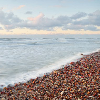 Deniz dalgaları ve sıçrama dokusu. Renkli gökyüzü suya yansıyor. Idyllic deniz manzarası. Kavramsal görüntü, uzun pozlama. Resimli bir manzara var. Arkaplan, duvar kağıdı, doğal desen, grafik kaynakları