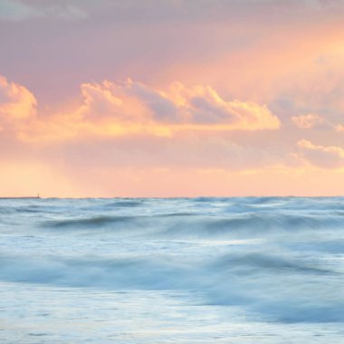 Deniz dalgaları ve sıçrama dokusu. Renkli gökyüzü suya yansıyor. Idyllic deniz manzarası. Kavramsal görüntü, uzun pozlama. Resimli bir manzara var. Arkaplan, duvar kağıdı, doğal desen, grafik kaynakları