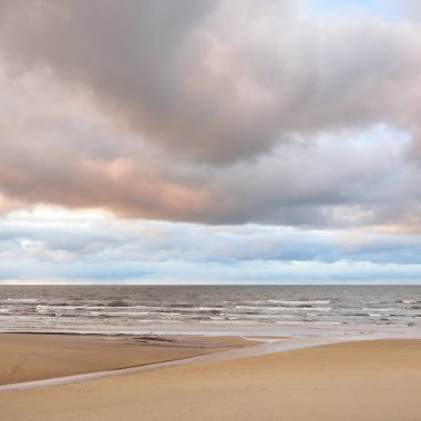 Gün batımında Baltık kıyısı. Kumsal manzarası (kum tepeleri). Dramatik günbatımı gökyüzü, parlayan bulutlar. Idyllic manzara. Doğa, tatiller, eğlence. Çevre turizmi. Panoramik görünüm