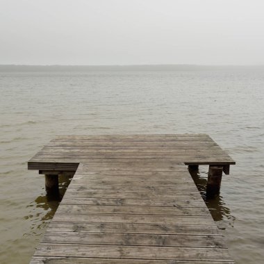 Yoğun bir siste orman nehri (göl). Ahşap iskele. Kasvetli gökyüzü, yağmur. Bulutlu bir gün. Idyllic manzara, kırsal manzara. Doğa, ekoloji, eko-turizm, yürüyüş, ekoloji beldesi, yerel turizm