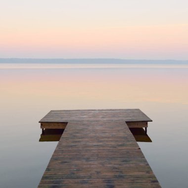 Forest lake (river) at sunrise. Wooden pier (boardwalk). Soft sunlight, mist, reflections on water. Idyllic autumn landscape. Pure nature, ecotourism, hiking, exploring