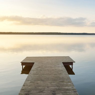 Orman Gölü (nehir) gün batımında. Ahşap iskele. Parlayan bulutlar, durgun ve berrak suda simetri yansımaları. Idyllic manzara. Doğa, ekoloji, ekolojik rezerv, eko-turizm, yürüyüş, tatiller