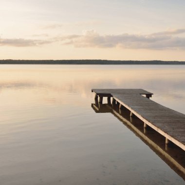 Orman Gölü (nehir) gün batımında. Ahşap iskele. Parlayan bulutlar, durgun ve berrak suda simetri yansımaları. Idyllic manzara. Doğa, ekoloji, ekolojik rezerv, eko-turizm, yürüyüş, tatiller
