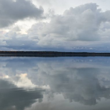 Gün batımında Orman Nehri (Lake). Dramatik gökyüzü, karanlık, parlak bulutlar. Kristal berrak suda simetri yansımaları. Panoramik sonbahar manzarası. Doğa, çevre, ekoloji, hava durumu, iklim değişikliği