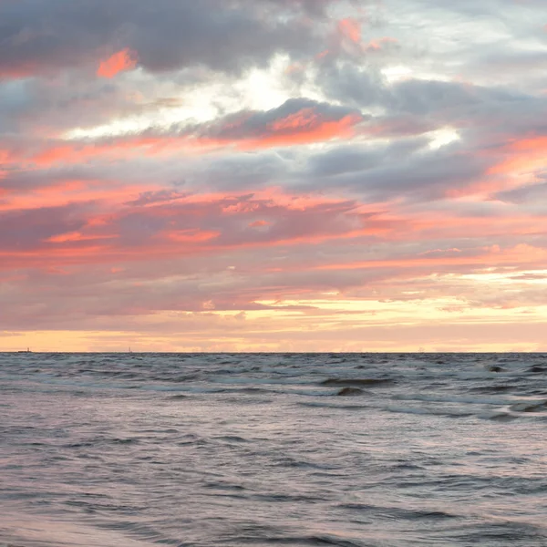 Gün batımında Baltık kıyılarından panoramik manzara. Dramatik fırtına gökyüzü, parlayan bulutlar, altın güneş ışığı. Dalgalar, su sıçratma. Doğa, çevre, kararsız hava