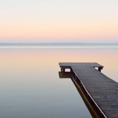 Forest lake (river) at sunrise. Wooden pier (boardwalk). Soft sunlight, mist, reflections on water. Idyllic autumn landscape. Pure nature, ecotourism, hiking, exploring