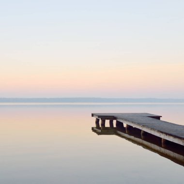 Orman Gölü (nehir) gün doğumunda. Tahta iskele (tahta iskele). Yumuşak güneş ışığı, sisler, suya yansıyan yansımalar. Idyllic sonbahar manzarası. Saf doğa, eko-turizm, yürüyüş, keşif.