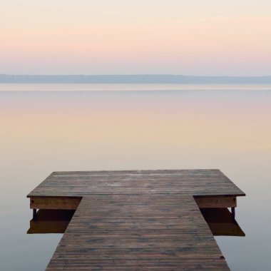 Forest lake (river) at sunrise. Wooden pier (boardwalk). Soft sunlight, mist, reflections on water. Idyllic autumn landscape. Pure nature, ecotourism, hiking, exploring