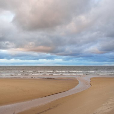Gün batımında Baltık kıyısı. Kumsal manzarası (kum tepeleri). Dramatik günbatımı gökyüzü, parlayan bulutlar. Idyllic manzara. Doğa, tatiller, eğlence. Çevre turizmi. Panoramik görünüm