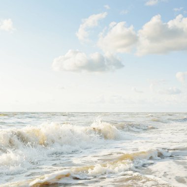 Fırtınadan sonra Baltık kıyıları. Gün batımı, yumuşak altın güneş ışığı. Su yüzeyi dokusu, çarpan dalgalar ve sıçramalar. Resimli panoramik manzara. Idyllic deniz manzarası. Doğa, çevre, ekoloji temaları