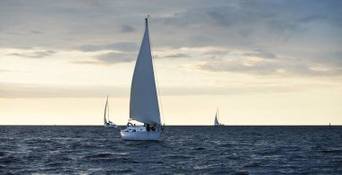 Baltık Denizi 'nde yelkenli bir yat. Gün batımı. Fırtınadan sonra dramatik bir gökyüzü, altın güneş ışığı. Ulaşım, seyahat, gezi, yat yarışı, spor, eğlence, boş zaman aktivitesi, yaşam tarzı