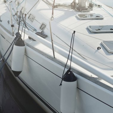 Beyaz modern yelkenli (kiralık ve satılık) yat limanındaki bir rıhtıma demirlemiş. Tahta meşe güvertesi. Denizcilik, ulaşım, amatör yelkencilik, tatiller, gezinti, eğlence kavramları