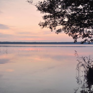 Gün batımında Orman Gölü. Yumuşak güneş ışığı, parlayan bulutlar kristal berrak suda simetri yansımaları. Idyllic manzara. Panoramik manzara. Doğa, ekoloji, çevrecilik. Barış ve neşe kavramları