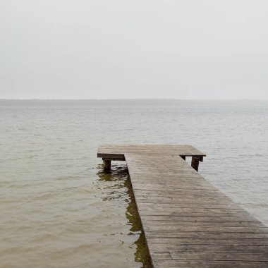 Yoğun bir siste orman nehri (göl). Ahşap iskele. Kasvetli gökyüzü, yağmur. Bulutlu bir gün. Idyllic manzara, kırsal manzara. Doğa, ekoloji, eko-turizm, yürüyüş, ekoloji beldesi, yerel turizm