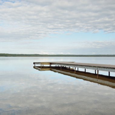 Orman nehri (göl) güneşli bir günde. Ahşap iskele. Clea gökyüzü, kristal berrak suda yansıyor. Idyllic manzara, kırsal manzara. Doğa, ekoloji, eko-turizm, yürüyüş, ekoloji beldesi, yerel turizm