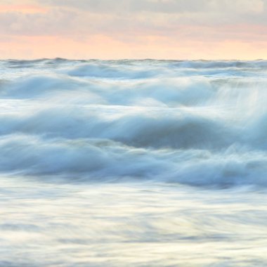 Deniz dalgaları ve sıçrama dokusu. Renkli gökyüzü suya yansıyor. Idyllic deniz manzarası. Kavramsal görüntü, uzun pozlama. Resimli bir manzara var. Arkaplan, duvar kağıdı, doğal desen, grafik kaynakları