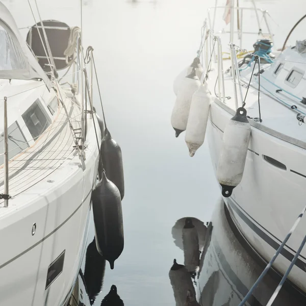 Beyaz modern yelkenli (kiralık ve satılık) yat limanındaki bir rıhtıma demirlemiş. Tahta meşe güvertesi. Denizcilik, ulaşım, amatör yelkencilik, tatiller, gezinti, eğlence kavramları