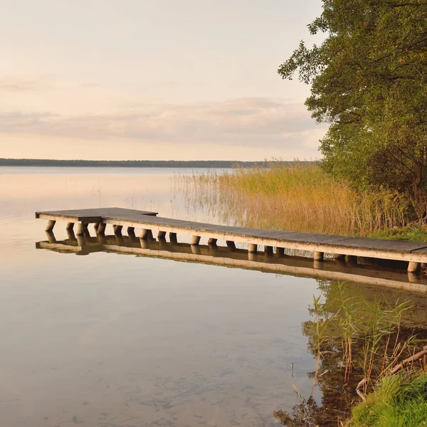 Orman Gölü (nehir) gün batımında. Ahşap iskele. Parlayan bulutlar, durgun ve berrak suda simetri yansımaları. Idyllic manzara. Doğa, ekoloji, ekolojik rezerv, eko-turizm, yürüyüş, tatiller