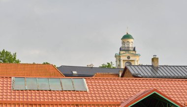Kırmızı kiremit çatılar ve saat kulesi. Letonya 'da sızıntı var. Aziz Nicholas Protestan Luteryan Kilisesi. Panoramik manzara. Seyahat yerleri, dönüm noktaları, geziler, kültür ve din temaları