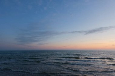 Gün batımında Baltık Denizi. Dramatik gökyüzü, mavi ve pembe parlayan bulutlar, yumuşak altın güneş ışığı, gece yarısı güneşi. Deniz manzarası, bulut manzarası, doğa. Panoramik görünüm