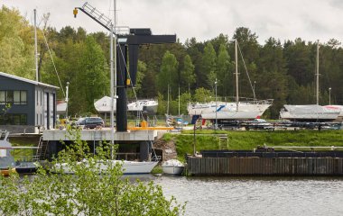 Zarif ve modern yelkenliler (kiralık ve satılık) bir rıhtıma demirlemiş ve yat limanında karada duruyor. Pavilosta, Letonya. Tamir ve hizmet, yaz tatili, gezi, boş zaman aktivitesi, spor