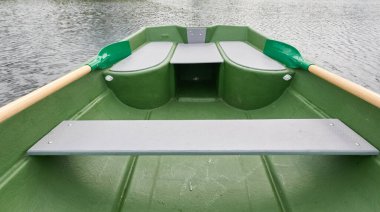 Orman gölünde küçük yeşil bir tekne. Dramatik bir gökyüzü. Sudaki yansımalar. Ulaşım, geleneksel zanaat, eğlence, boş zaman aktivitesi, sağlıklı yaşam tarzı, yerel turizm kavramları