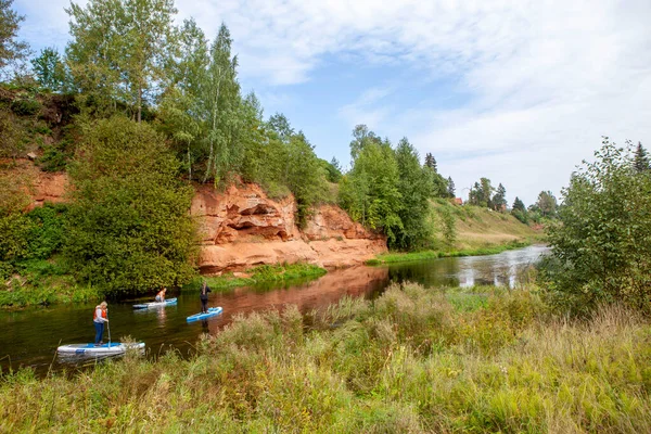 Oronzh Nehri 'nin kıyısındaki Devonian kayalıkları yakınında SUP binen kadınlar. Siverskaya ekolojik yolu ya da Yaşam Okulu 'nun yolu. Yerleşim yeri Siversky. Gatchina bölgesi. Leningrad bölgesi. - Rusya. 28 Ağustos 2021
