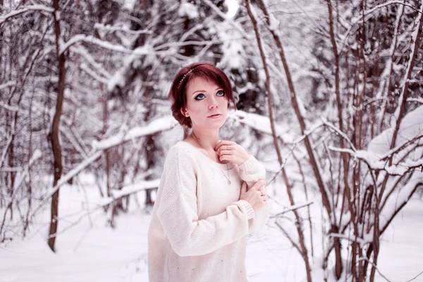 Мечтающая девушка стоит в снежном лесу — стоковое фото
