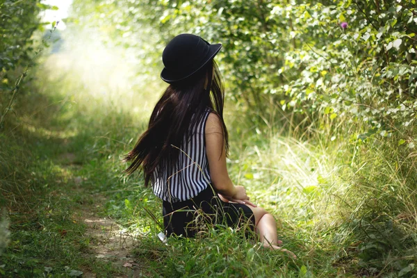 Menina de chapéu preto sentado no chão — Fotografia de Stock