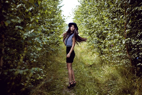 Fashionabla flicka viftande håret i skogen — Stockfoto
