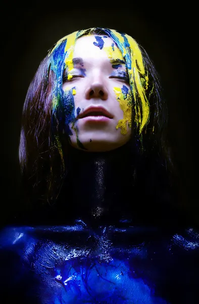 Menina pintada de azul e amarelo no fundo preto — Fotografia de Stock