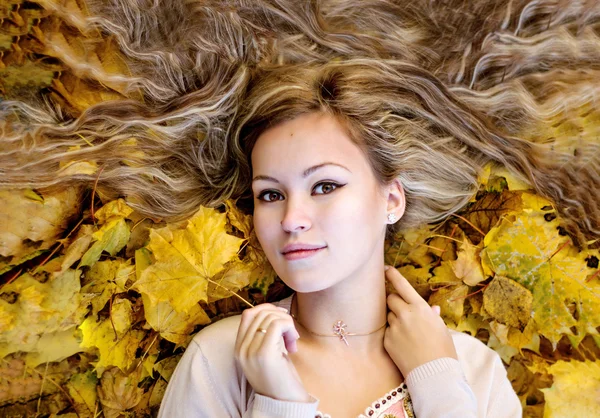 Hermosa mujer acostada con hojas de otoño — Foto de Stock