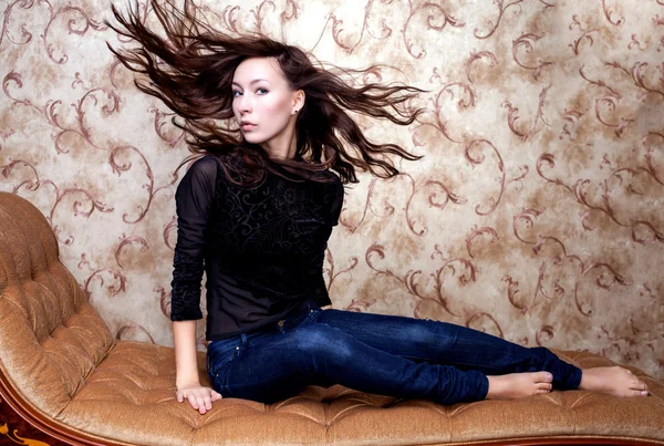 Bella ragazza agitando i capelli castani sul divano vintage — Foto Stock