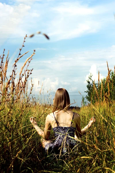 Entspannte Frau macht Yoga auf sonnigem Feld — Stockfoto