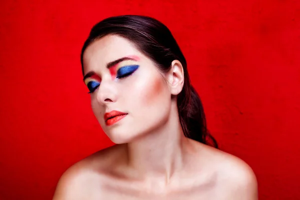 Belleza retrato de cerca de la mujer con maquillaje colorido en el fondo rojo — Foto de Stock