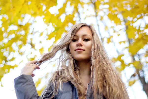 Wunderschöne junge Frau auf gelben Herbstblättern Hintergrund — Stockfoto