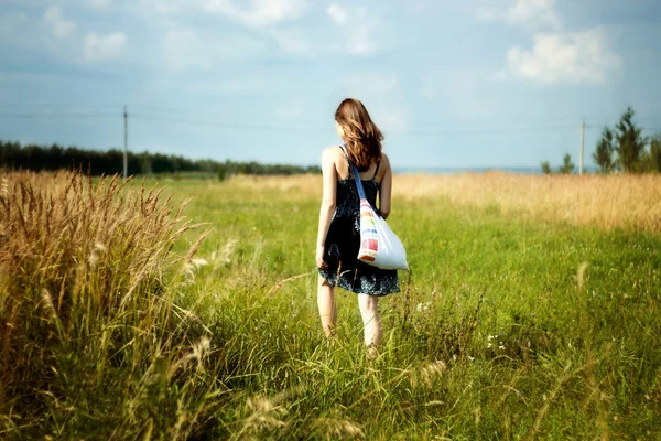 Woman walking through sunshine green and yellow corn field — Stock Photo, Image