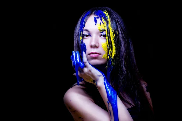 Krása módní zblízka portrét ženy namalovaný modré a žluté na černém pozadí — Stock fotografie