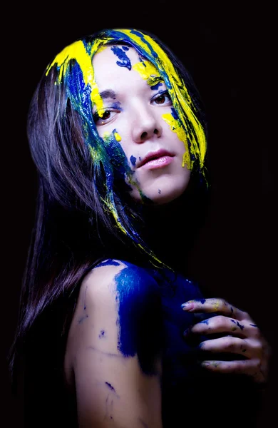 Moda uroda zbliżenie portret kobiety, malowane niebieski i żółty na czarnym tle — Zdjęcie stockowe