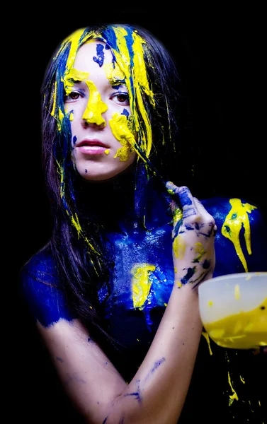 Moda de belleza de cerca retrato de mujer pintada de azul y amarillo con pinceles y pintura sobre fondo negro — Foto de Stock