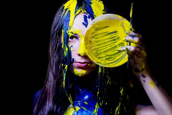 Moda de belleza de cerca retrato de mujer pintada de azul y amarillo con pinceles y pintura sobre fondo negro — Foto de Stock