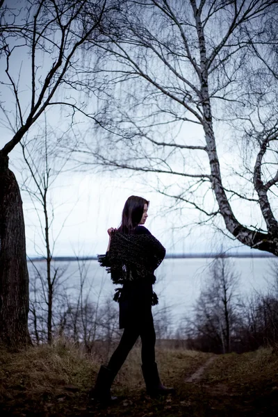 Woman in black dress dancing in cold dark forest background — Stock Photo, Image